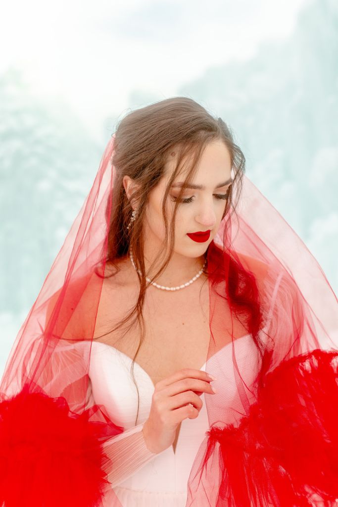 A dreamy close-up of Kalli in Wed Utah's Barbie dress, surrounded by our red drop veil.