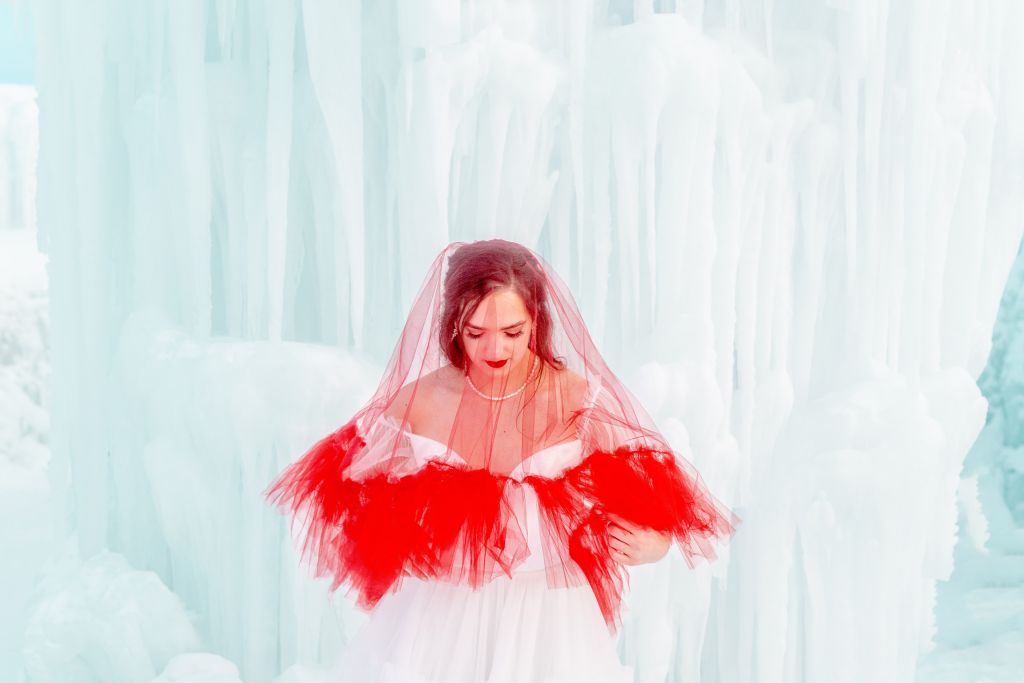 The red drop veil with a tulle ruffle trip is the statement piece of this bridal shoot. Kalli shows how it would look brought in front.